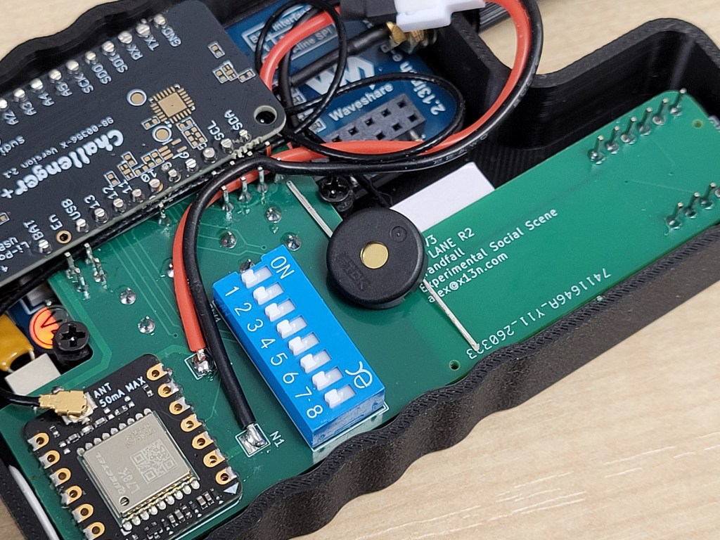 A photograph of the MFD v3 with the back plate removed, exposing the printed circuit board and multiple soldered components. A piezo buzzer is loosely placed on the circuit board.