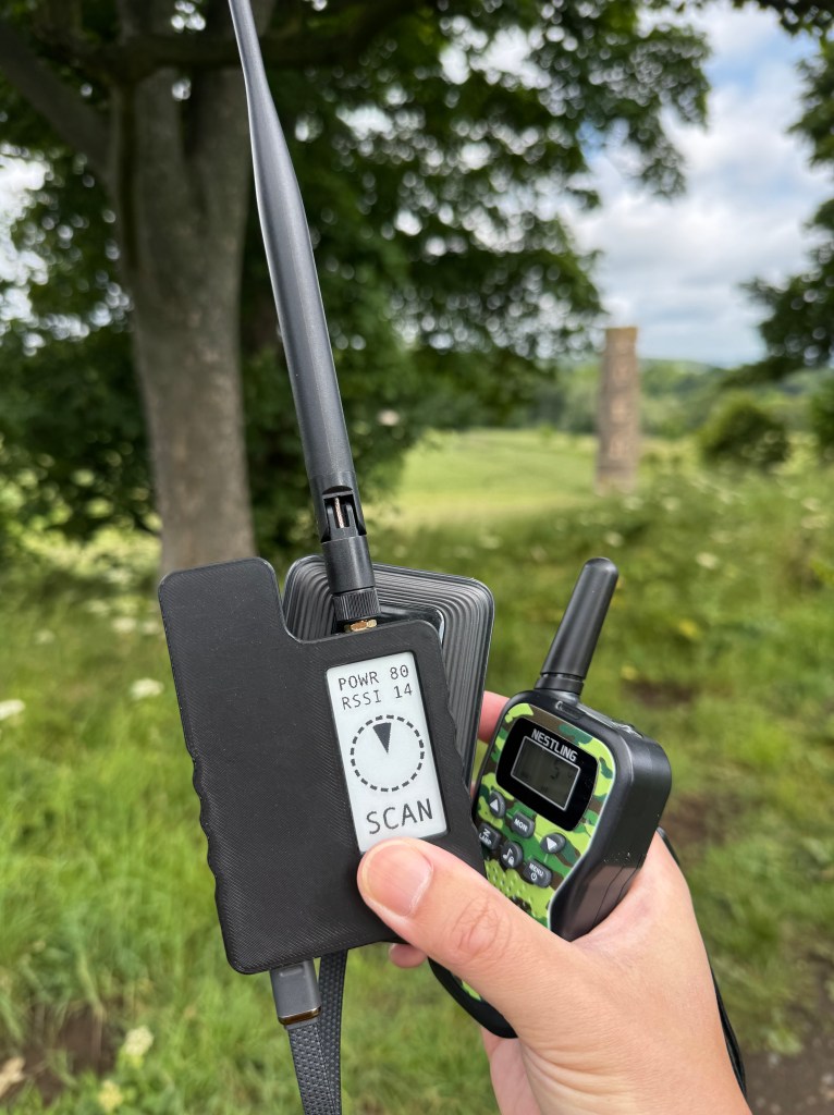 A hand holding walkie talkie and a black device with an ePaper display showing SCAN